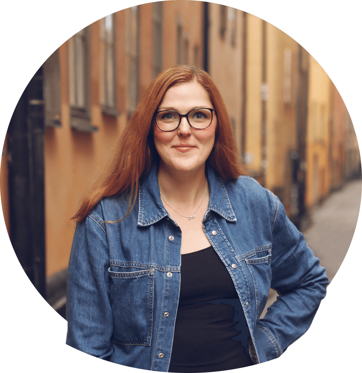 Line med briller på og halvblondt hår i hestehale, smilende kledd i mørk bluse. Foto.